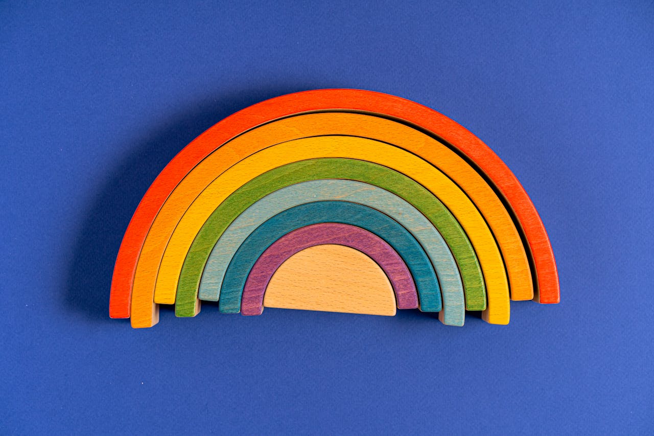 Vibrant still life of a rainbow made from wooden blocks on a blue backdrop.