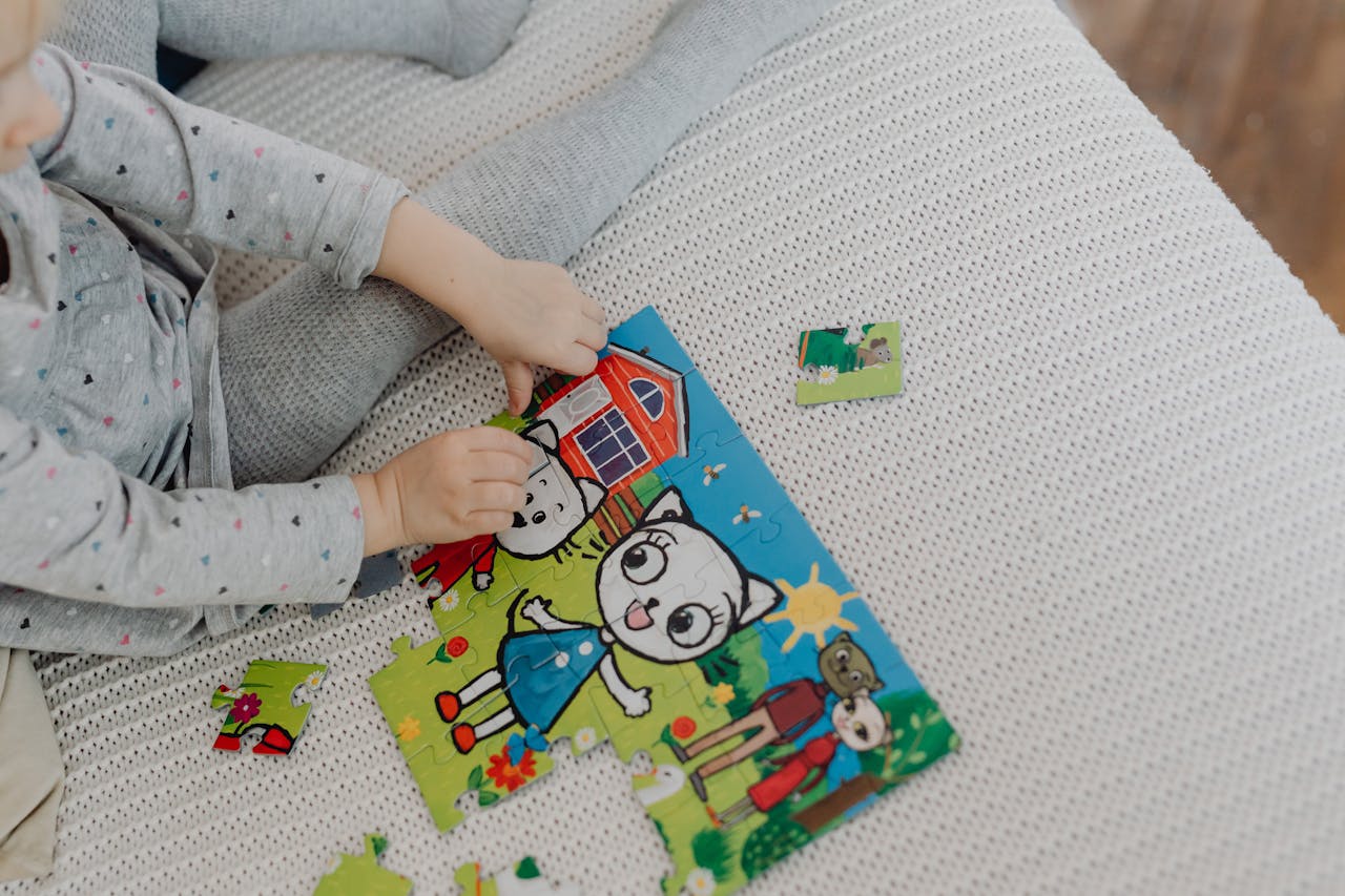 A child assembling a colorful cartoon puzzle indoors, capturing playtime creativity.